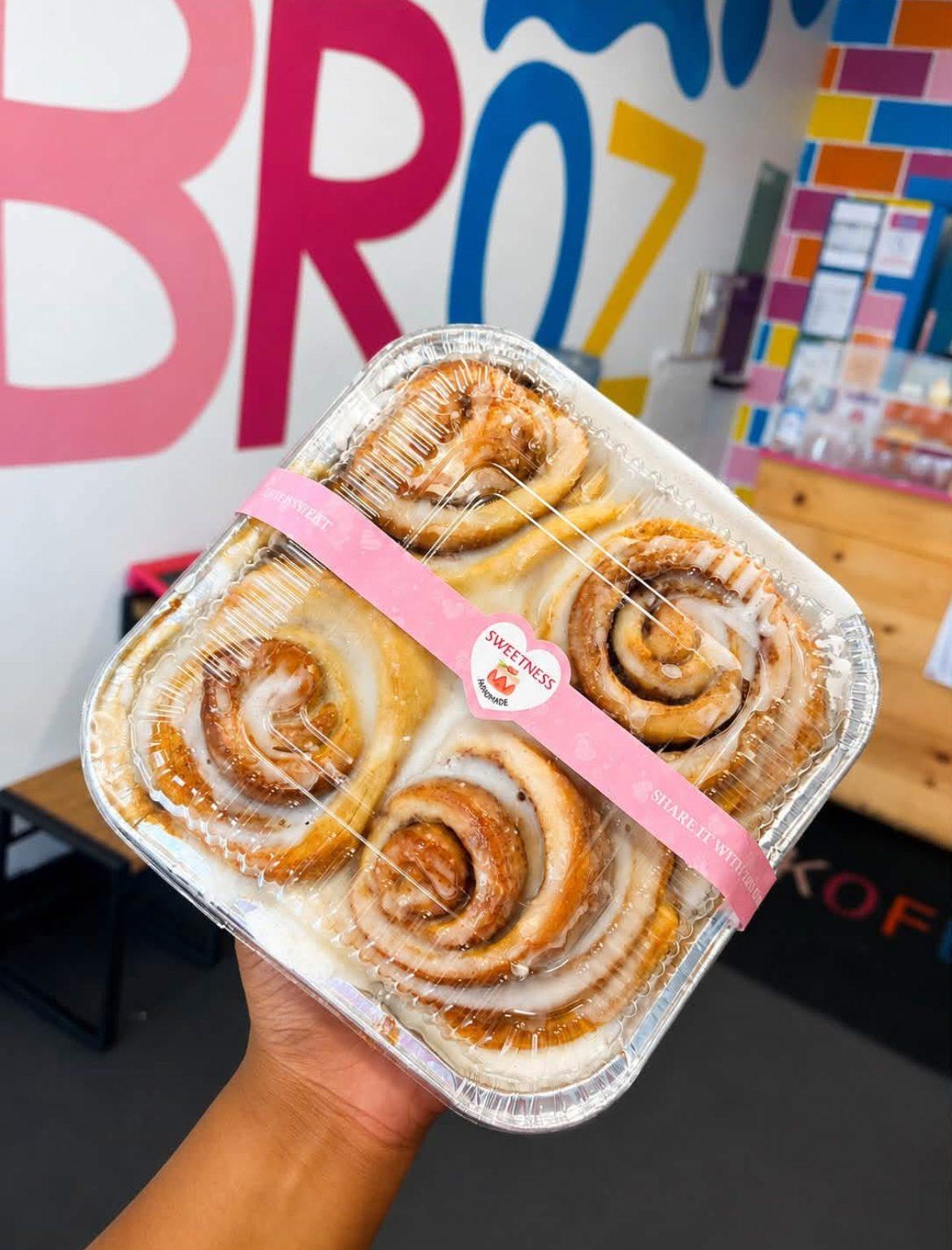 Four fresh-glazed cinnamon rolls in a Kofee Broz takeaway pack